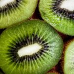 Home Detailed shot of fresh green kiwi slices, showcasing juicy texture and seeds.